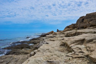 İspanya 'daki güzel ve renkli Mallorca adasındaki beyaz bulutlar ve dağ arka planıyla mavi turkuaz deniz suyu ve gökyüzü ile ıssız kayalıkların manzaralı manzarası..