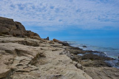 İspanya 'daki güzel ve renkli Mallorca adasındaki beyaz bulutlar ve dağ arka planıyla mavi turkuaz deniz suyu ve gökyüzü ile ıssız kayalıkların manzaralı manzarası..