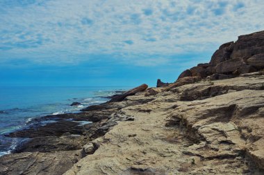 İspanya 'daki güzel ve renkli Mallorca adasındaki beyaz bulutlar ve dağ arka planıyla mavi turkuaz deniz suyu ve gökyüzü ile ıssız kayalıkların manzaralı manzarası..