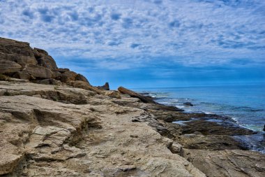 Bir koy ve kaya ile Kayalık kıyı şeridi, su yüzeyi üzerinde bölünmüş görünümü, Akdeniz, İspanya. Masmavi deniz, dalga ve mavi gökyüzü. Deniz ufku ve bulutlu derin mavi gökyüzü ile Seascape.