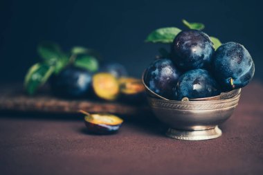 Kahverengi yüzey arka plan üzerinde gümüş vintage kase Organik taze erik. Sağlıklı yaşam tarzı yaz vejetaryen gıda. Kır bahçe meyve konsepti. Güzel natürmort. Kopyalama alanı ile tonlu görüntü.