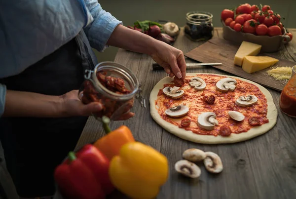 Cook hands. Close up on hands, some ingredients around on table. Fresh original Italian raw pizza, preparation in traditional style. Ingredients and spices for making homemade pizza on wooden table.