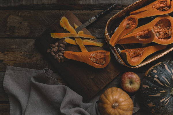 Fresh organic vegetables on rustic wooden background. Healthy natural food. Sliced and whole pumpkins. Cooking ingredients. Autumn seasonal eating. Rural still life. Top view. Toned image.