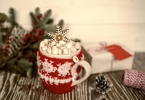 Warm cup of cacao or coffee with marshmallows and gingerbread in winter, holidays concept, Christmas mood. Mug and gift boxon the vintage wooden background. Concept of winter holidays and coziness.