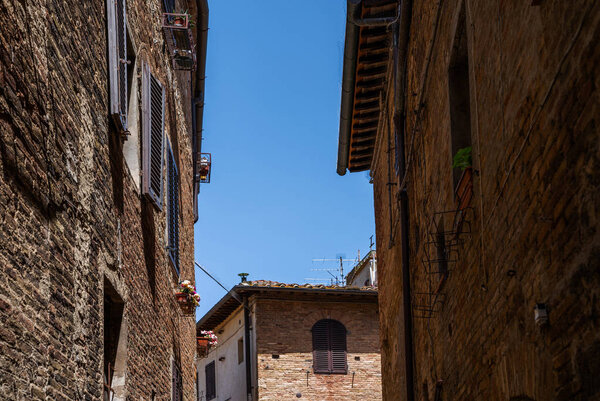 Beautiful view of cozy street of San Gimignano and Old Town of medieval town in the sunny day. Tuscany, Italy.
