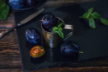 Siyah taş tabakta yaprakları olan erikler. Rustik yemek geçmişi. Taze organik meyveler. Sağlıklı yiyecekler. Tonlu görüntü. Metniniz için boş alan.