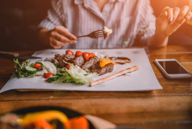 Baharatlı Izgara kuzu bacak sebze ve otlar üzerinde bir kavurma ile dökme demir. Sebzeli ızgara kuzu. Sağlıklı gıda. Yemek ve eğlence kavramı. Kadın gıda ile masada yemek yiyorlar. Tonlu görüntü.