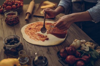 Taze orijinal İtalyan ham pizza ve malzemelerin üzerine ahşap masa, hazırlık, geleneksel tarzda. Ev yapımı pizza ev bir mutfak ahşap bir masa üzerinde yemek kadın. Pişirme, yiyecek ve insan kavramı.