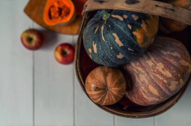 Beyaz rustik tahtalarda sonbahar sebze. Vintage hasır sepet sonbahar süslemeleri. Kabak, kabak, kabak ve elma ile bir bereket. Kopya alanı ile tonlu görüntü. Seçici odak. Hasat zamanı.