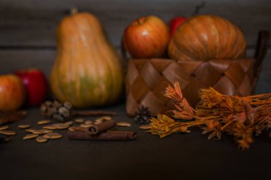 Baharat, sonbahar yaprakları ve sıcak koyu ahşap masa üzerinde koniler. Arka planda ufuk renkli sebze. Organik sebze hasır sepetin içinde. Çevre gıda ve hasat kavramı. Seçici odak.