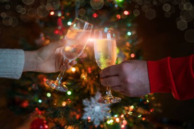 Şerefe! Womam ve adam arka planda Noel iç şampanya flüt ile tezahürat. Tatil konsepti. Akşam ışıkları parlıyor. Yeni yıl kutlaması. Tonlu görüntü. Seçici odaklama.