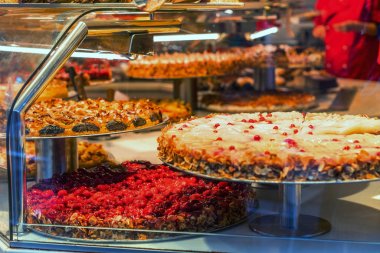 Tatiller ve kış konsepti. Vitrinde yaban mersinli ve bademli Noel pastaları. Alman pastanesi. Meyveli ve meyveli kekler. Pasta dükkanının cam vitrininde farklı tipte pastalar..