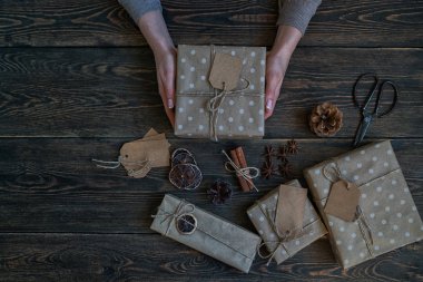 Mutlu Noeller ve mutlu tatiller. Kadın el yapımı hediyeler hazırlar. Hediyeler, dekorasyon, köknar konileri, rustik ahşap arka plan üzerinde anis yıldız. Noel aile gelenekleri. Seçici odak. Tonlu görüntü.