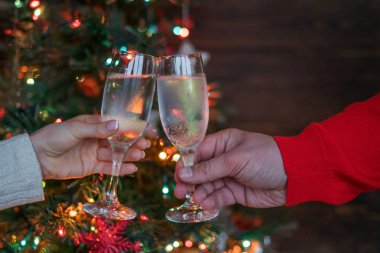 Noel aydınlatmaları ve şampanya bardağı. Bardak şampanya, kutlama ve Noel ve mutlu yeni yıl onuruna kızartma insanlarla elleri. Şampanya flüt ile tezahürat çift.