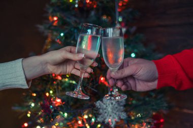 Noel ağacı parlayan ışıklara karşı kadeh kaldıran iki kadeh şampanya. Tatil ve birliktelik bir aile Noel ve Happy New Year. Parti zamanı. Şampanyalı bir çift. Seçici odaklama.