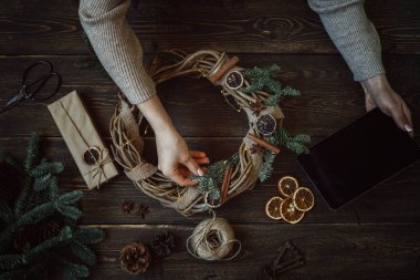 Süslemeleri, çelenk ve çam kozalağı ile Noel arka plan. Koyu vintage ahşap tahta üzerinde noel ağacı dalları ve kuru baharat yapılmış çelenk oluşturma. Yeni Yılınız Kutlu Olsun. Tonlu görüntü. Yumuşak odaklama.