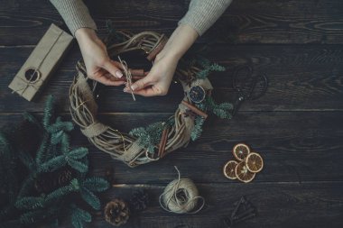 Süslemeleri, çelenk ve çam kozalağı ile Noel arka plan. Koyu vintage ahşap tahta üzerinde noel ağacı dalları ve kuru baharat yapılmış çelenk oluşturma. Yeni Yılınız Kutlu Olsun. Tonlu görüntü. Yumuşak odaklama.