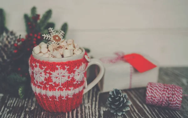 Cup of hot cocoa with marshmallows and gingerbread in the form of snowflakes against rustic background with Christmas fir branches of bokeh. Perfect winter time treat. Toned image. Soft focus.