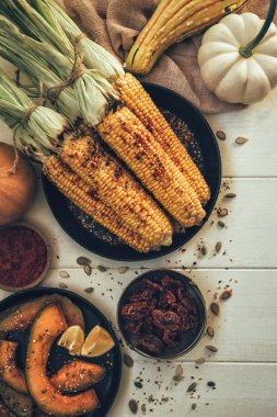 Sonbahar sağlıklı pişirme arka plan. Şükran Günü ızgara akşam yemeği. Düz-mısır koçan, pişmiş kabak, baharat ve taze çiftlik sebzeler ahşap masa üzerinde, üst görünümü.
