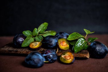 Bahçe erikleri masada. Yaprakları ile taze erik kapatın. Erik yaz veya sonbahar hasadı. Tonlu görüntü. Seçici odaklama.