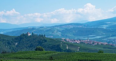 Val di Non 'un yaz sezonundaki panoramik manzarası. Güney Tyrol, İtalya 'nın Trentino-Alto Adige bölgesindeki üzüm bağları ve elma bahçesi manzarası. Arka planda güzel küçük bir Alp köyü.