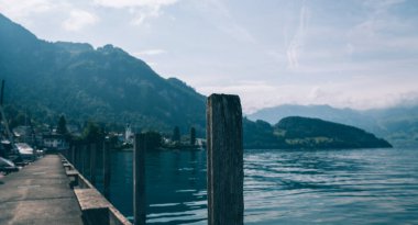 Gersau kasabası yakınlarındaki Lucerne Gölü manzarası. Arka planda İsviçre Alpleri. İsviçre, Schwyz Kantonu. Yaz mevsimi boyunca marinada turkuaz bir suyla demirlenmiş tekneler ve lüks yatlar. Seyahat ve tatil.