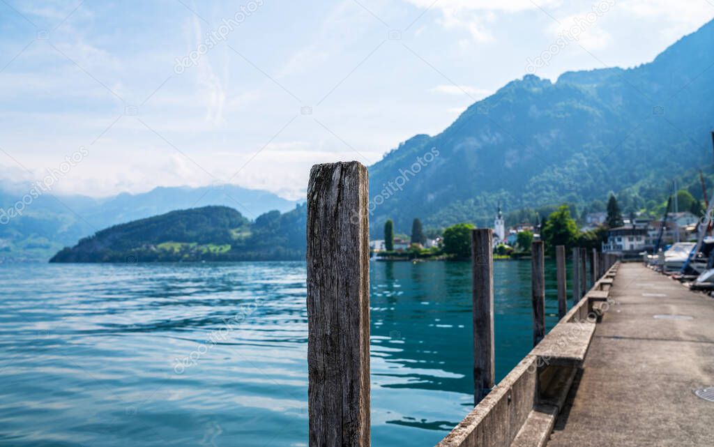 View of Lake Lucerne near Gersau town. Swiss Alps in the background. Canton of Schwyz, Switzerland. Boats and luxury yachts moored in marina on a turquoise water, during a summer season. Travel and vacation.