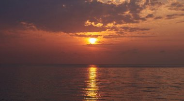 Cennet manzarası tropikal ada plajı, gün doğumu çekimi. Tropikal denizin üzerinde güzel bir gün doğumu. Uzaktaki eski balıkçı teknesi.