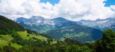 Dağları, küçük bir köyü, yeşil çayırları ve İsviçre Alpleri 'ndeki bulutlu mavi gökyüzüyle muhteşem bir yaz manzarası. Oberland, İsviçre.