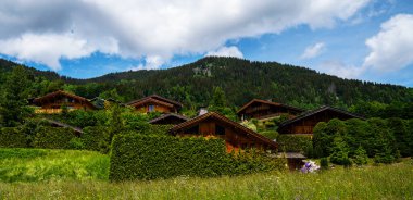 Alps, İtalya 'da ahşap evler. Yeşil dağ eteklerinde kereste ve keresteli kır evleri. Doğal ahşaptan yapılmış samimi çevre dostu evler, aileler için bungalovlar..