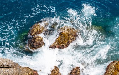 Su yüzeyinin arka plan görüntüsü. Deniz dalgaları ve kayalık kıyı manzarası.