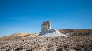 Görkemli kireçtaşı oluşumu, engebeli araziyi keşfeden yürüyüşçülerle açık mavi gökyüzüne karşı dimdik ayakta duruyor. Eşsiz kaya kulesi kurak manzara, macera ve doğal harikayla çelişiyor..