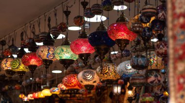 Türkçe mozaik kolye ışıklarından oluşan canlı bir sıra, çeşitli renklerde, sıcak bir şekilde parlayan, kapalı bir alanda parlak ve renkli bir duvar halısında asılı duran..