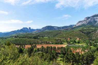 İspanya 'daki Serra del Montsia' nın nefes kesici manzarası, engebeli dağlar, yemyeşil vadiler ve dağınık tarım arazileri. Berrak mavi gökyüzünün altındaki canlı yeşillik.