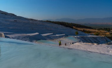 Türkiye 'deki Pamukkale' nin çarpıcı manzarasında mineral zengini termik havuzlar yer alıyor. Parlak beyaz teraslar koyu mavi gökyüzü ile tezat oluşturuyor..