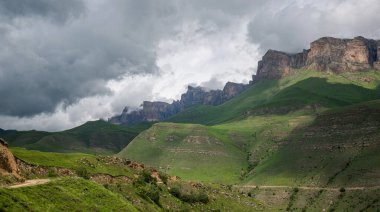 Baharda bulutlu ve yağmurlu bir gün, alçak fırtına bulutları. Bahar dağı manzarası. Vadinin muhteşem manzarası ve Georgia 'nın yemyeşil otlakları. Vadi yüksek sıradağlarla çevrili..