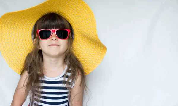 Hasır şapka ve güneş gözlüğü renkli elbise beyaz zemin üzerine stüdyoda, sevimli küçük kız portresi. Metin için yer kopyalayın