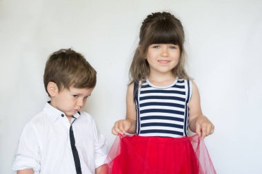 Serin küçük gri arka plan üzerinde poz çocuklar. İki beyaz kardeşler ağabey ve kardeş. İnatçı çocuk yapması ve kızgın mutluluk kardeşiyle poz için istemiyor