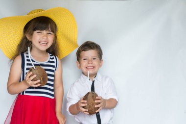 Mutlu çocuklar Hindistan cevizi kokteyl tutarak ve gülümseyen yaz giysileri. Reklam banner kopya alanı ile