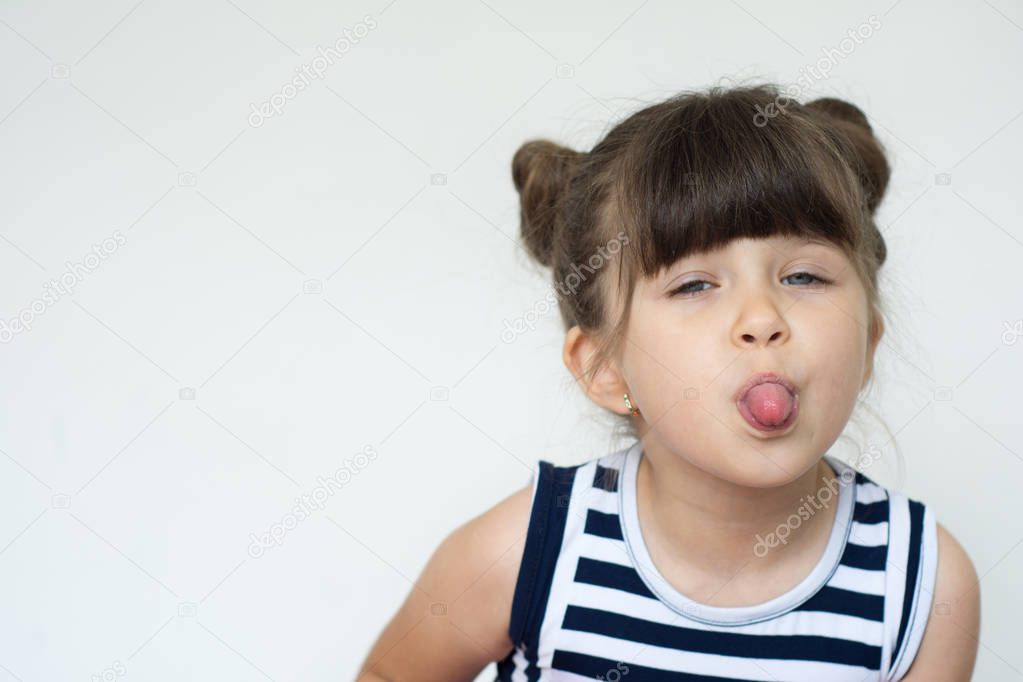 Portrait of joyful beautiful child shows tongue on a white background