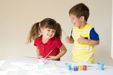 Neşeli çocuklar oynarken. Yürümeye başlayan çocuk ve bebek birlikte boyama. Erkek ve kız evde ya da günlük bakım.