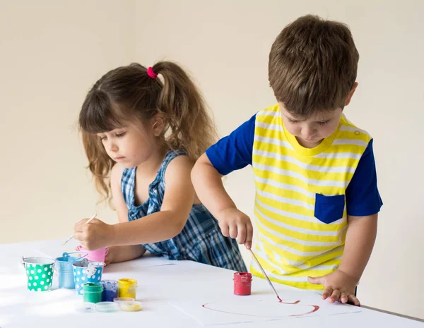 Joyful children playing and painting at kindergarten or playschool.