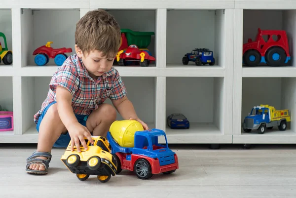 Baby boy  with toy car. Kindergarten background.