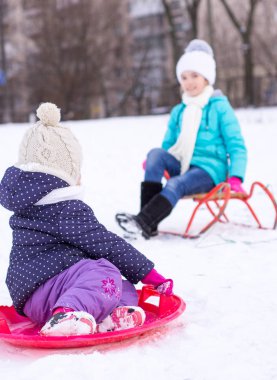 İki kız kardeş bir yılbaşı parkta yürümek ve bir kızak binmek. Kış masal. 