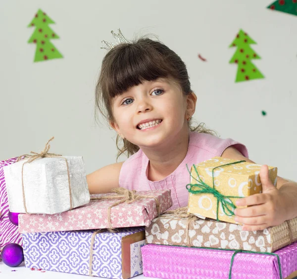 Smiling funny child holding Christmas gift in hand. Christmas holidays