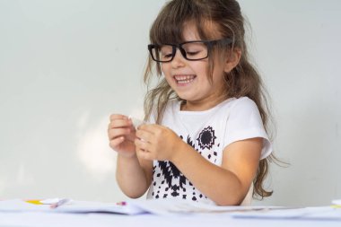 Evde gözlük ile güzel bir mutlu okul öncesi çocuk kız portresi ödev yapma. Okul, eğitim kavramı.