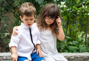 Kız ve erkek kardeşim. İki küçük çocuk birbirlerine sevgi bahçesinde ile sarılma. Aile sevgisi. Kavram dostluk. Ağlayan arkadaşı kız yatıştırır. 
