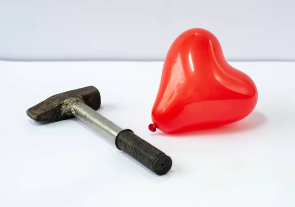 Red heart and hammer. Love affair or breakup and divorce concept. Not true love. End of relationship.