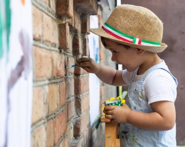 İki yıl eski çocuk duvara çiziyor. Boya fırçası ve suluboya ile küçük çocuk.