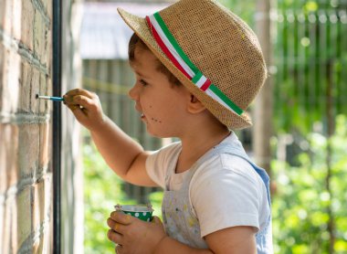 İki yıl eski çocuk duvara çiziyor. Boya fırçası ve suluboya ile küçük çocuk.